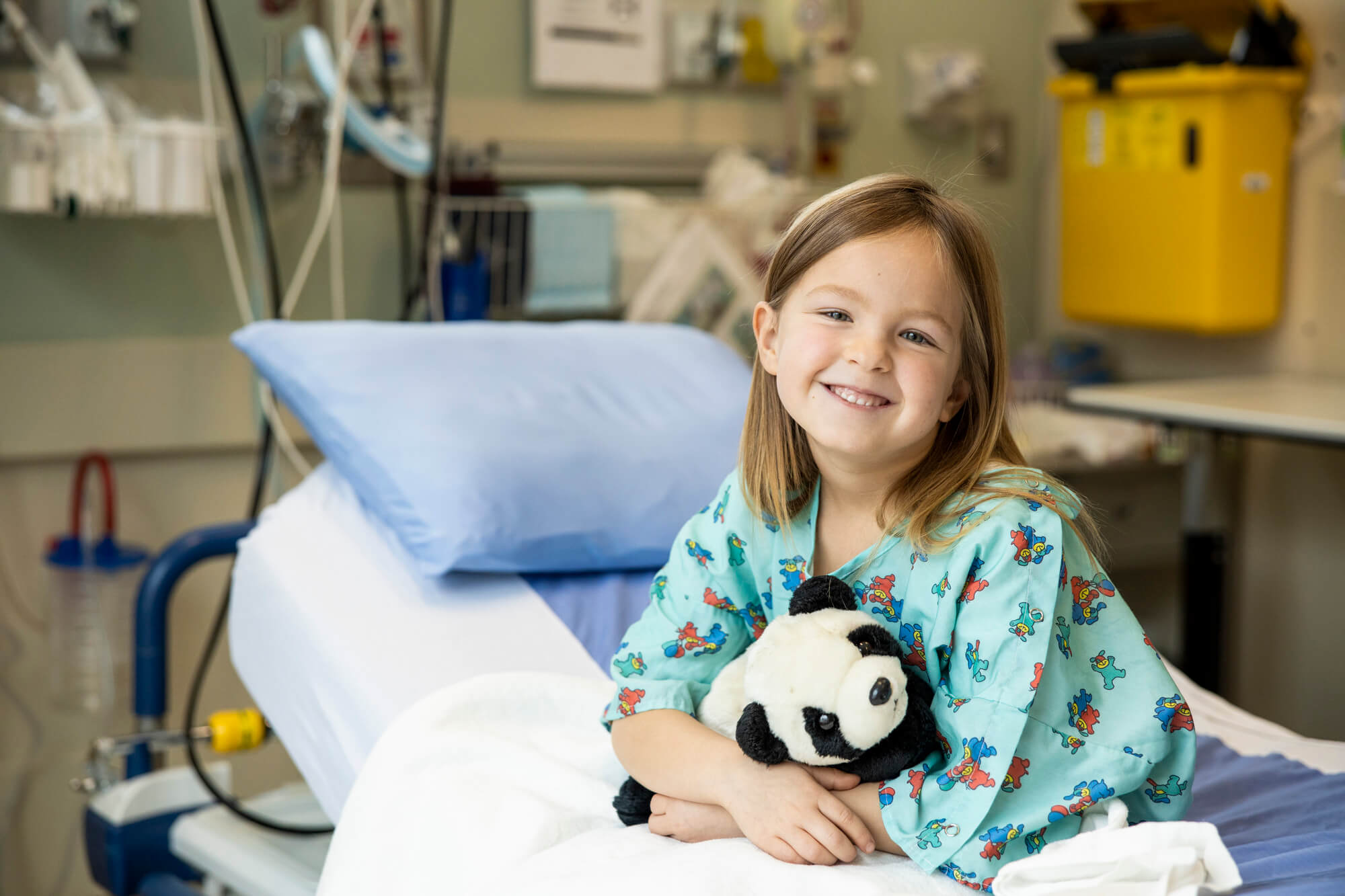 Girl in Hospital Bed Hugging Stuffed Toy
